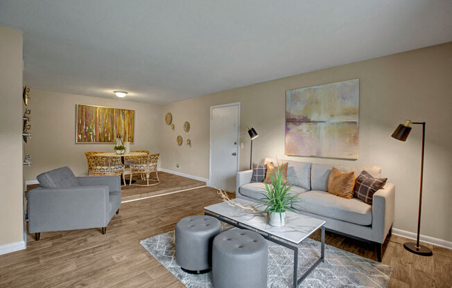 Living room, wood-like flooring, large couch and sofa chairs, sliding glass door to balcony