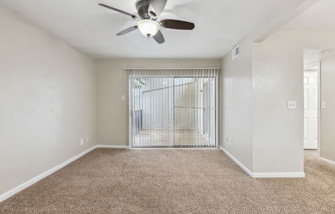 an empty living room with a ceiling fan and a window