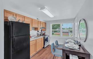 a kitchen with a black refrigerator and a table and chairs