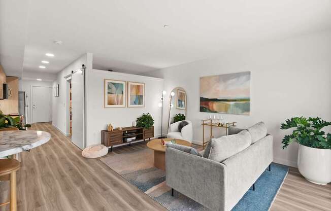 A living room with a grey couch and a painting on the wall.