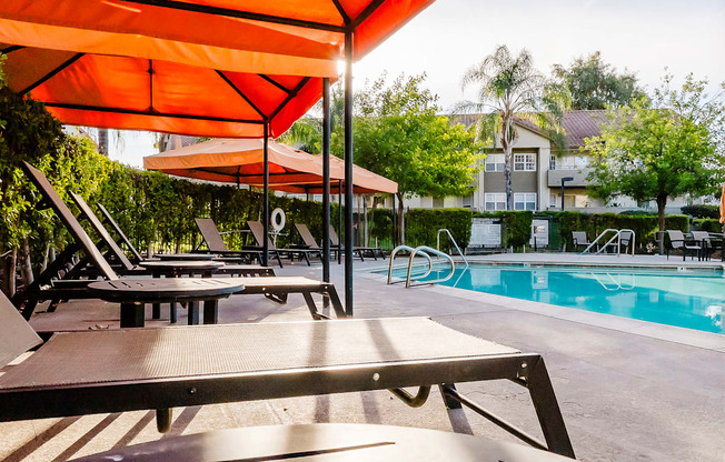 A poolside area with sun loungers and an orange umbrella.
