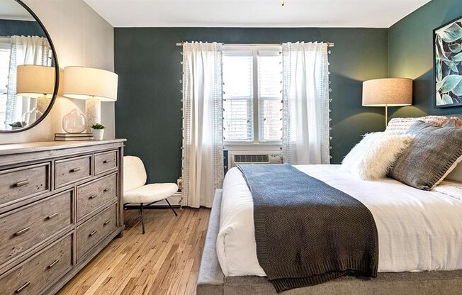 Large bedroom featuring queen size bed, full size dresser, and accent chair
