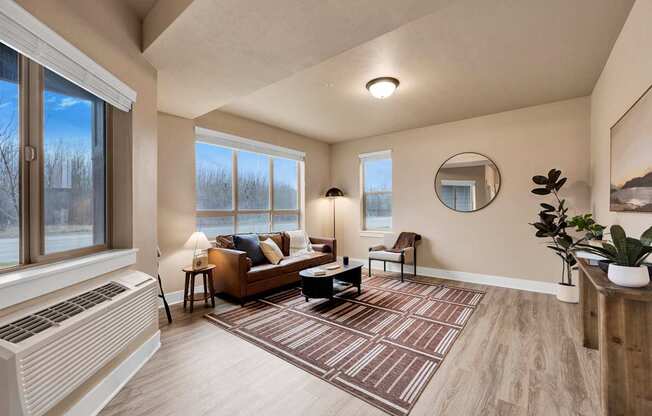A living room with a brown couch and a round mirror on the wall.