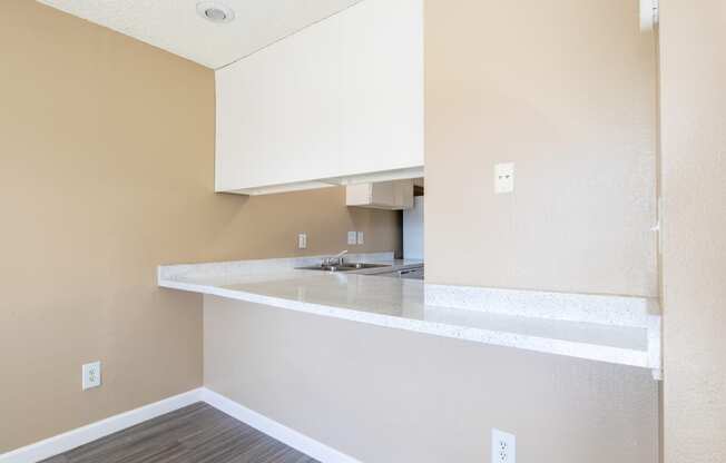 an empty kitchen with white cabinets and a counter top