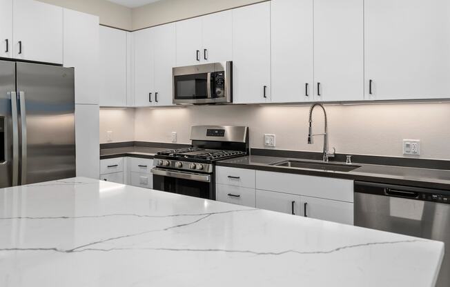 an all white kitchen with stainless steel appliances and white counter tops