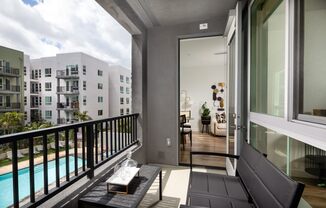 A balcony with a black couch and a pool in the background.