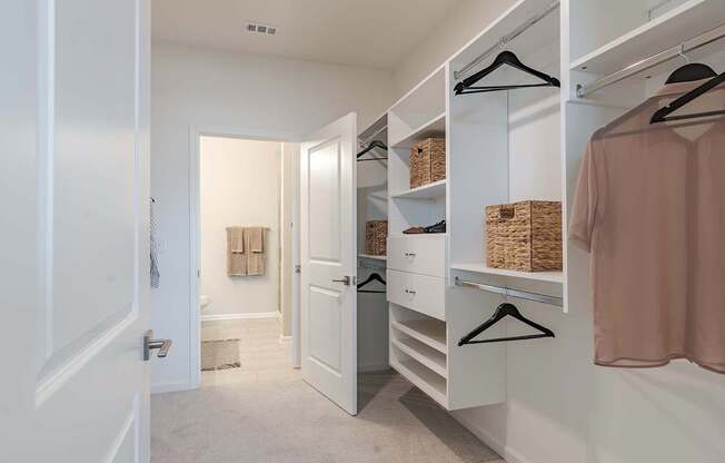a walk in closet with a large white closet with shelves and hangers