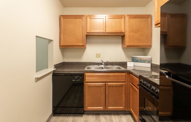 This is a photo of a kitchen with honey oak cabinets and black appliances in a 560 square foot 1, 1 bath apartment at Park Lane Apartments in Cincinnati, OH.