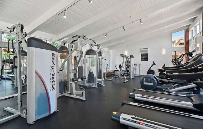 A gym with a variety of equipment including treadmills, weights, and exercise machines.