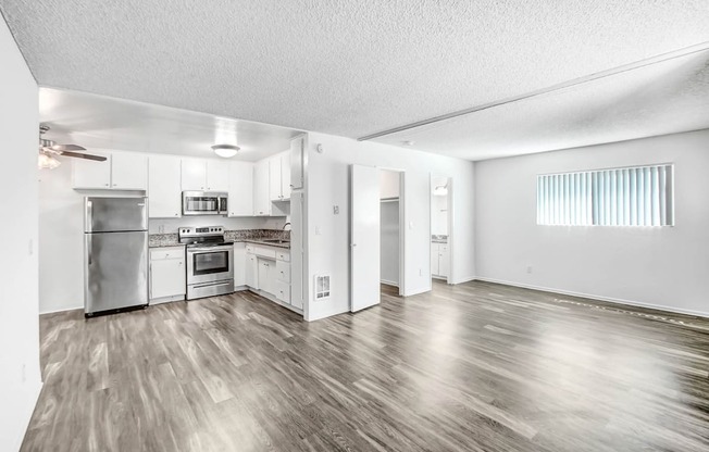 the living room and kitchen of an apartment with stainless steel appliances