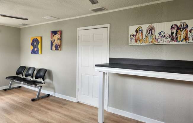 a room with a desk and chairs and paintings on the wall