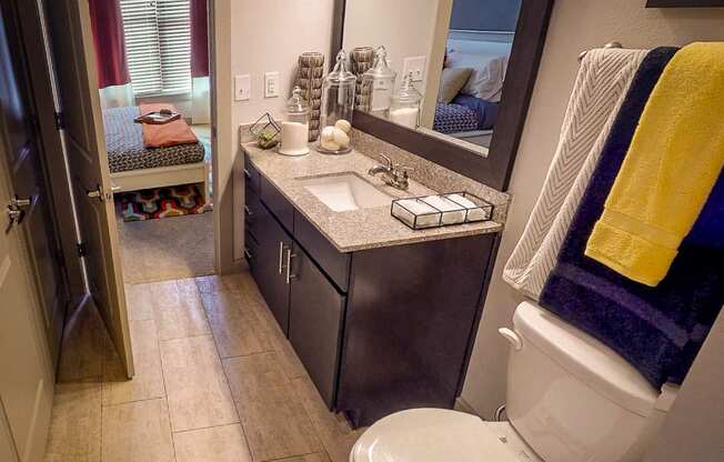 A bathroom with a toilet, sink, mirror, and a towel hanging on the towel rack.