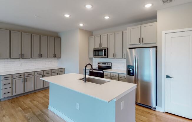 a kitchen with a large center island with a sink and a refrigerator