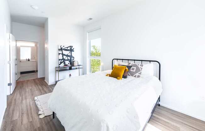 A bedroom with a white bed and a yellow pillow.