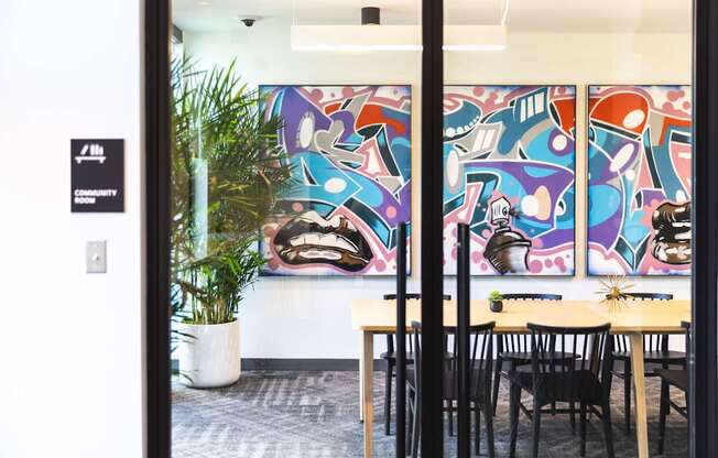 A room with a table and chairs and a painting on the wall.