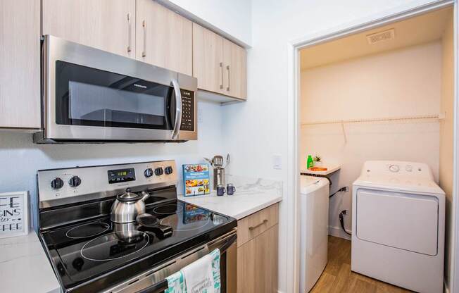 A small kitchen with a stove, microwave, and washing machine.