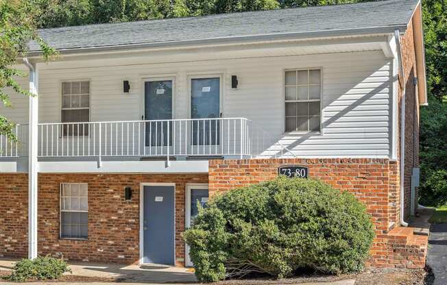 the front of a brick building with a porch and a sign on the side