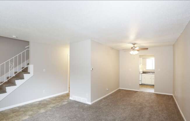 the living room of an empty house with a ceiling fan