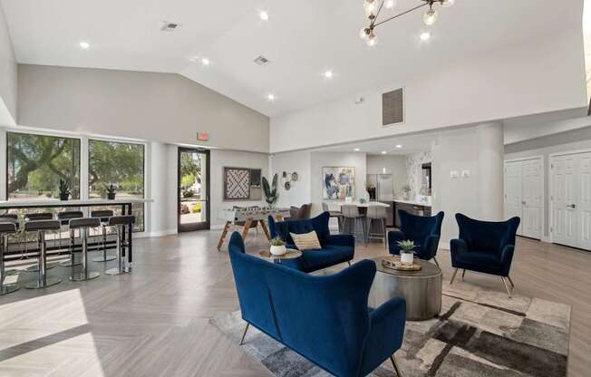 A spacious living room with blue chairs and a dining table.
