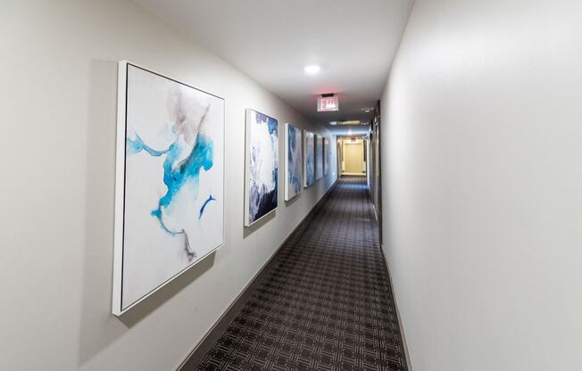a hallway with paintings on the wall and a carpeted floor
