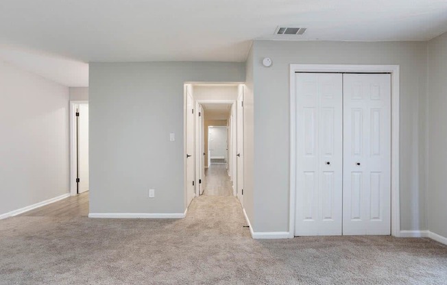 A long hallway with white doors and carpeted floors.