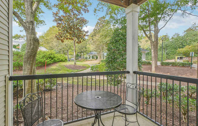 A patio with a table and chairs overlooking a garden.