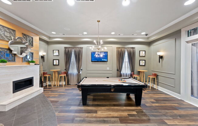 a game room with a pool table, fireplace, and a television