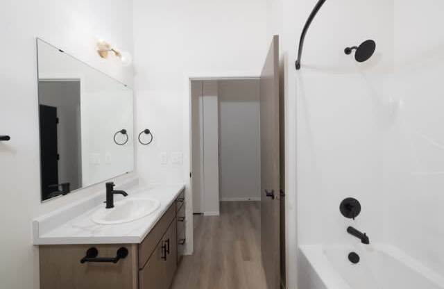 A bathroom with a sink, mirror, and bathtub.
