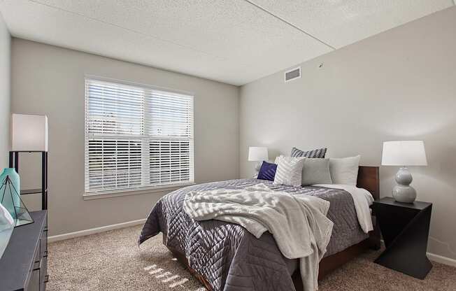A bedroom with a bed, nightstand, and window.
