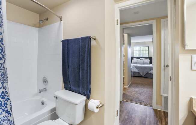 a bathroom with a toilet and a tub and a bedroom