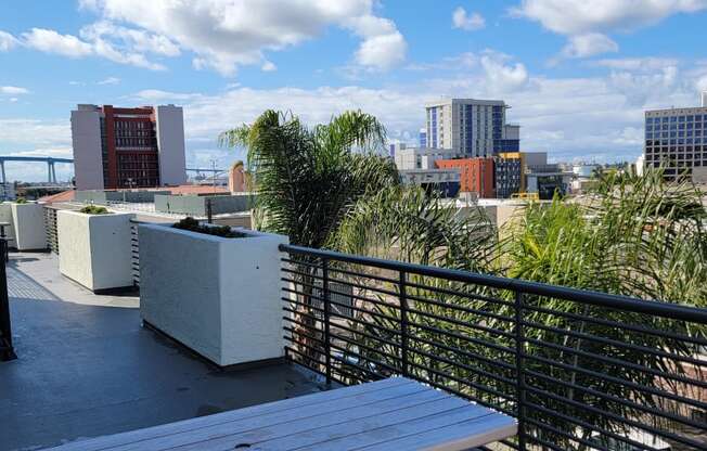 Patio tables, planters, and skyline view of San Diego at Atrium Apartments.