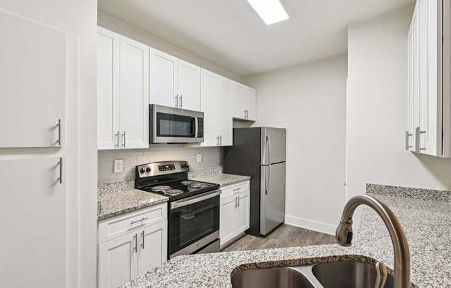 A renovated kitchen with white cabinets, granite countertops through out and stainless steel appliances