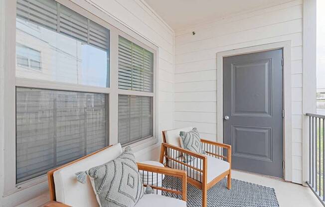 A balcony with a white couch and a grey door.