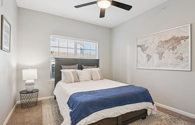 A bedroom with a bed, a ceiling fan, and a world map on the wall.