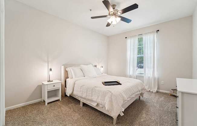 A bedroom with a bed, nightstand, and window.