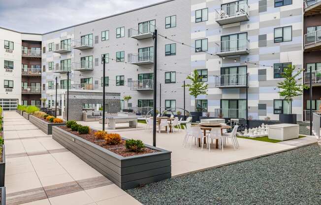 an open courtyard with tables and chairs in front of an apartment building