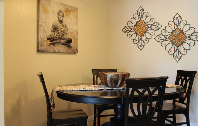 A dining room with a table and chairs and a Buddha picture on the wall.