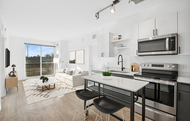 Model Kitchen with Dark Cabinets, Wood-Style Flooring and View of Living Room at Stella Apartments located in New Carrollton, MD.