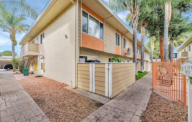 A beige house with a brown roof and a brown fence.