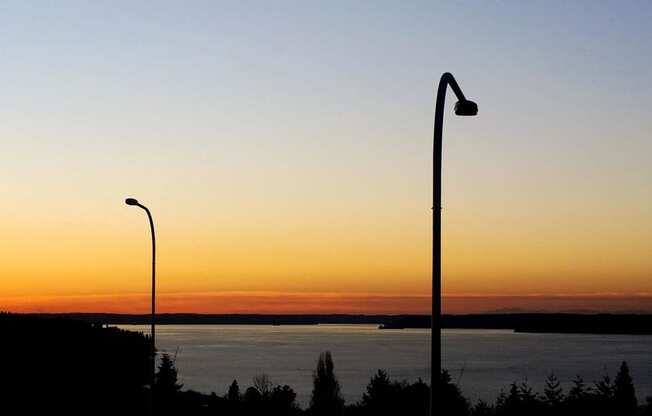 a sunset over a body of water and two street lights