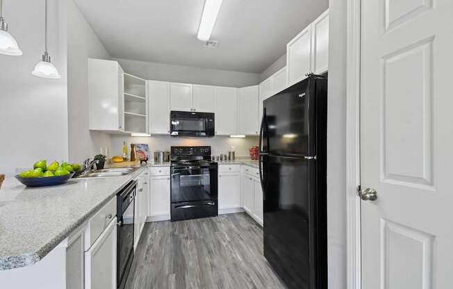 A black refrigerator is in a white kitchen.