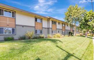 A row of apartment buildings with green lawns in front.