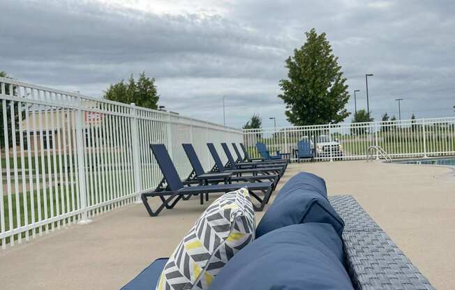 A row of blue sun loungers are on a patio.