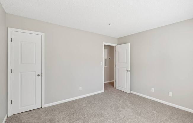 A room with two doors and a carpeted floor.