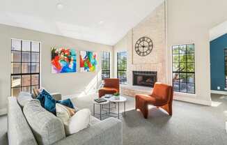 Cozy lounge space in clubhouse with fireplace, couch and orange plush seats at Bandera Crossing apartments in San Antonio, TX