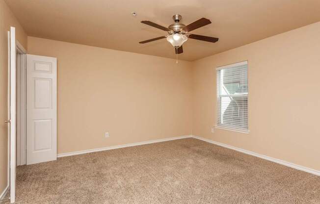 A room with a ceiling fan and carpeted floor.