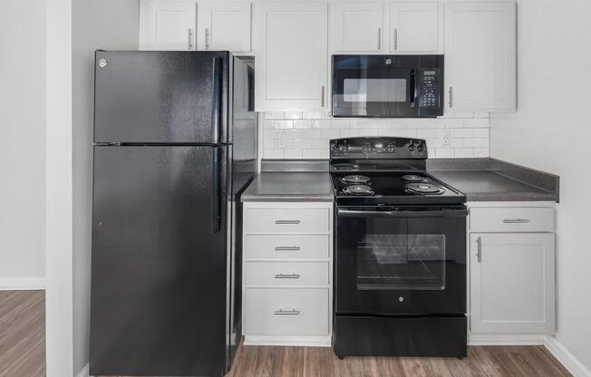 A kitchen with black appliances and white cabinets at Ashley Oaks Apartments in Greensboro, NC