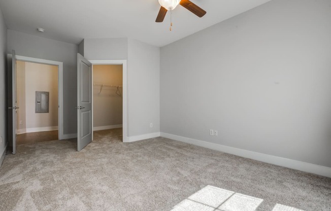 bedroom with carpeted flooring, ceiling fan, and walk-in closet