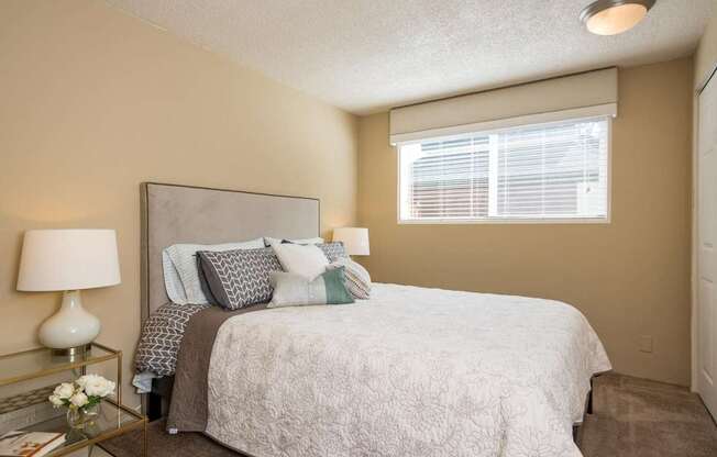 A bedroom with a bed, nightstand, and window.