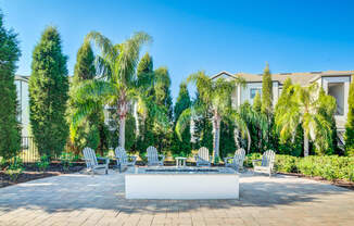 an outdoor patio with palm trees and chairs and a fountain